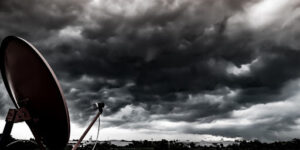 Satellite dish facing to dark storm cloud